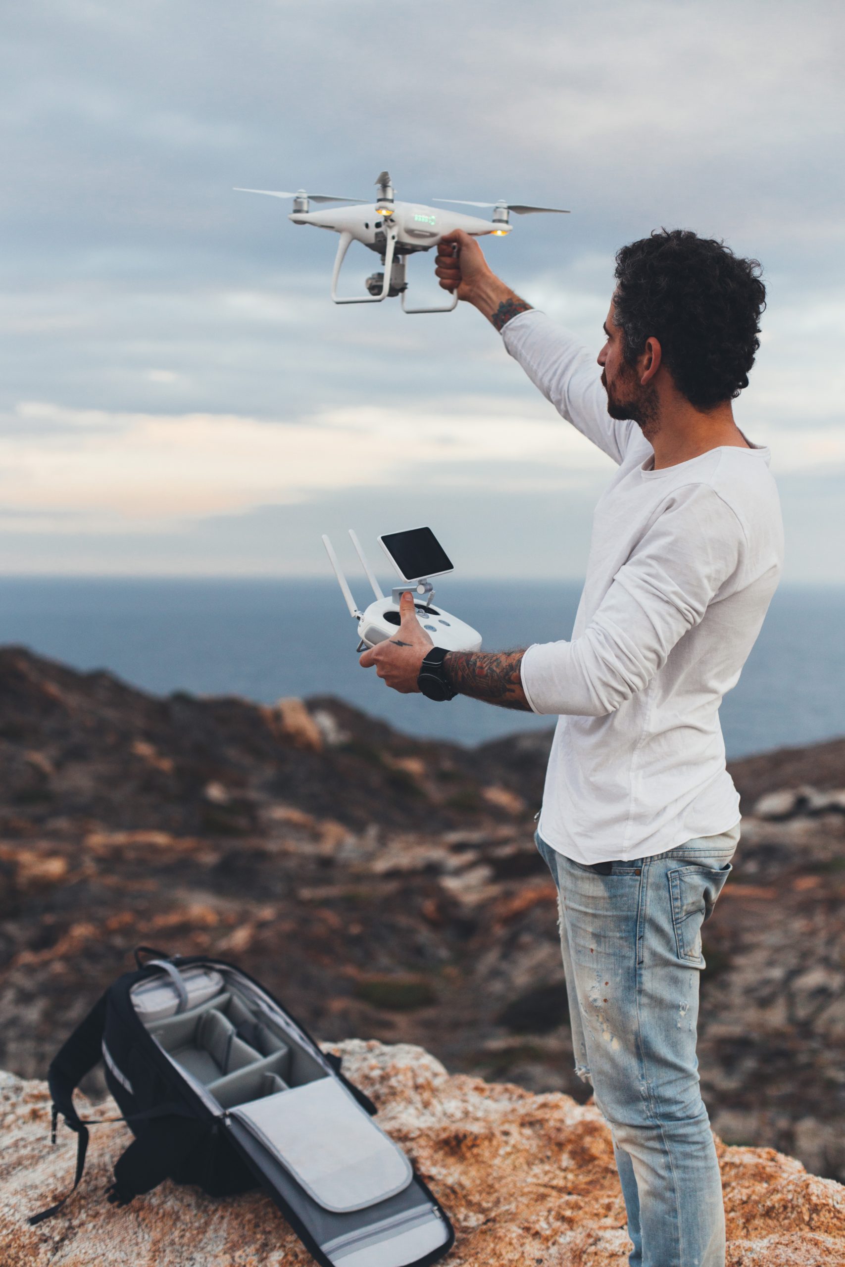 Professional drone pilot or stock photographer, prepares to fly high technology futuristic drone into air, sets up controls and remote connection. Ready to explore nature and cliffs from top